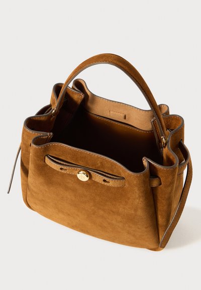 Ruda zomšinė rankinė su struktūrine forma, viena viršuje esanti rankena ir auksiniu mygtuko uždarymu. Interjere yra lygus pamušalas ir kišenė.