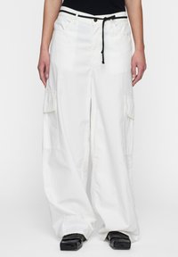 Witte cargo broek met een relaxte pasvorm, voorzien van twee zijzakken en een trekkoord in de taille. Soepele stof en wijde pijpen.