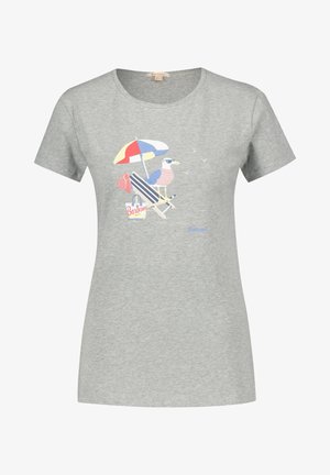 Szara koszulka z grafiką mewy w pasiastym t-shircie na leżaku, pod parasolem plażowym, z torbą, ręcznikiem i latającymi ptakami.