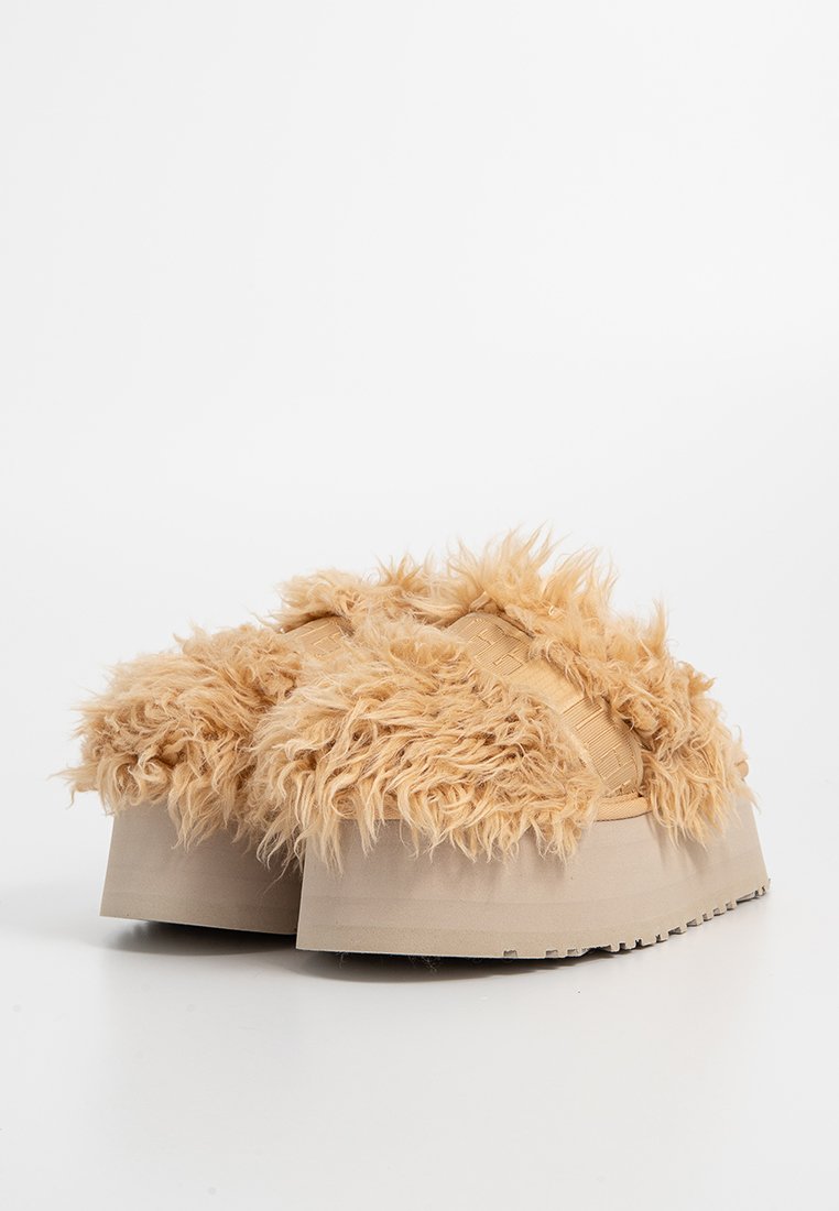 Chaussures à plateforme brun clair avec un dessus en fourrure texturée et moelleuse, présentant une semelle en caoutchouc lisse et sans matériel ni accents visibles.
