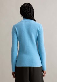 Light blue ribbed sweater with a fitted design, long sleeves, and a high collar. Textured fabric highlights simplicity and warmth.