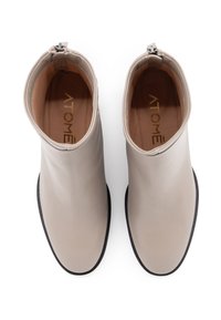 Stivali alla caviglia beige realizzati in pelle liscia con punta arrotondata, design minimalista, suola nera e chiusura con zip sul retro per una facile calzata.