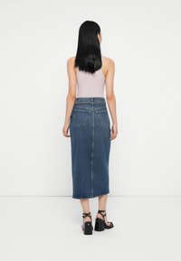 Denim svārki, vidēja garuma, augstā jostasvietā ar taisnu siluetu, sānu šķēlumu un divām aizmugurējām kabatām. Uzvilkti ar vieglu tank topu un augstpapēžu sandālēm.