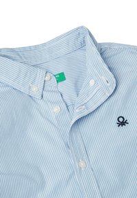 Camicia a righe blu chiaro con colletto button-down, bottoni bianchi e logo ricamato blu navy sul petto. Materiale in cotone, texture liscia.