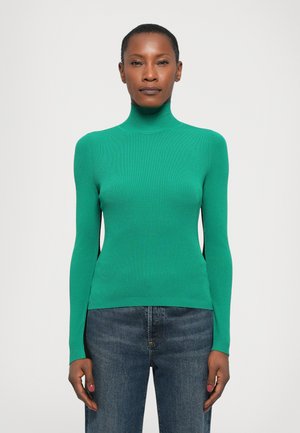 Green ribbed turtleneck sweater with long sleeves, fitted design, soft texture, and a solid color. Paired with dark denim jeans.