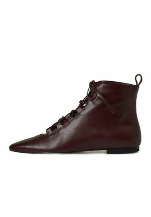 Stivali ankle in pelle marrone con punta affusolata, caratterizzati da un design con lacci e una suola piatta. Texture liscia con una finitura morbida.