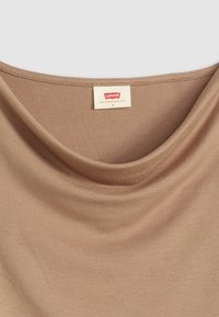 Beige scoop-necked topp laget av myk stoff, med en glatt tekstur. Merket leser "Levi's, San Francisco, CAL, S" plassert nær halslinjen.