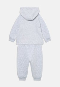 Sivé detské športové oblečenie s kapucňou a prešívanými nohavicami. Mäkkučký materiál, rebrované manžety a uvoľnený strih.