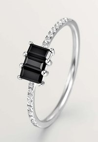 Anillo de plata esterlina que presenta dos piedras negras rectangulares, acentuado por pequeñas piedras transparentes a lo largo de la banda para darle un detalle adicional.