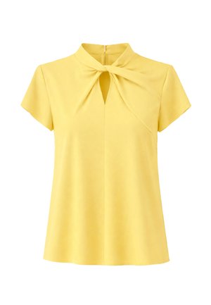 Żółta bluzka z krótkim rękawem z detalem skręconego węzła i wycięciem w kształcie klucza przy dekolcie, z zamkiem błyskawicznym z tyłu.