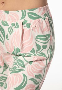 Lichte katoenen broek met een bloemenpatroon in roze en groene tinten, voorzien van een zachte tailleband en een klein strikje aan de zijkant.