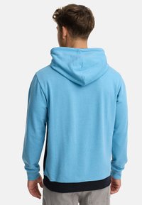 Haut en coton bleu avec une grande capuche, des poignets et un ourlet côtelés. Présente une section inférieure noire contrastante et une texture lisse.