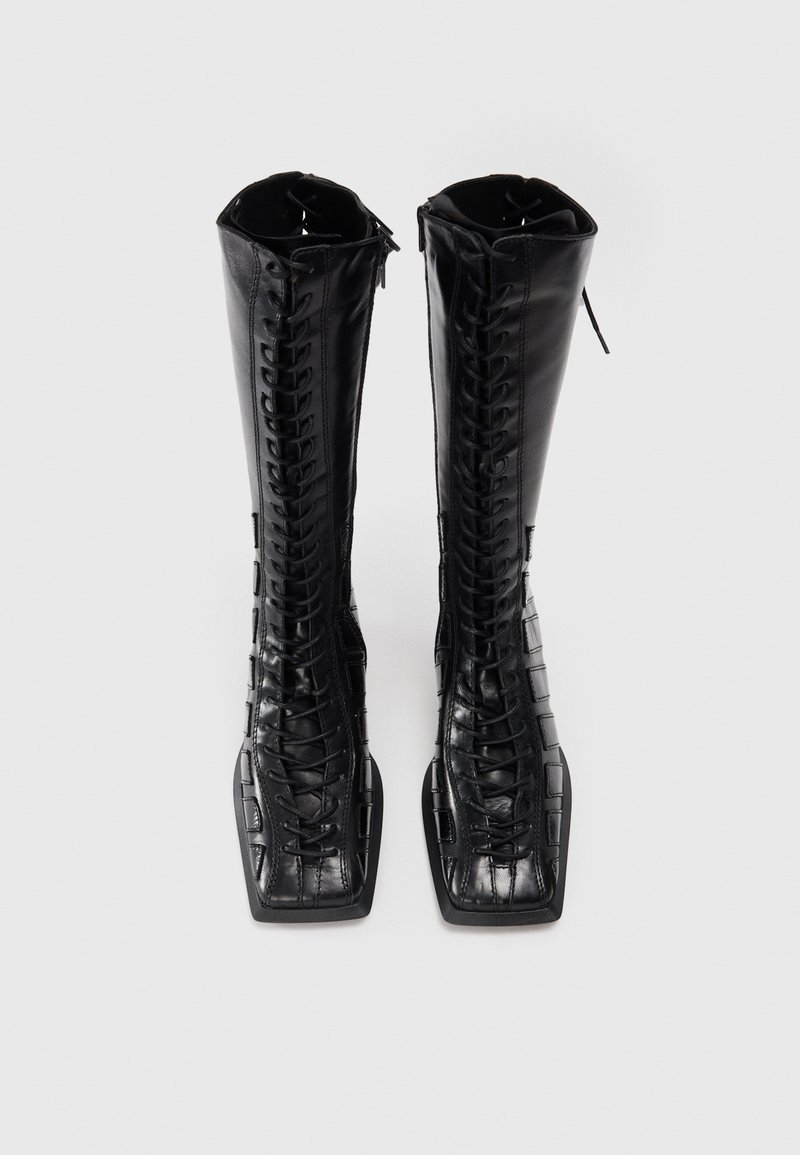Schwarze knöchelhohe Stiefel aus glattem Leder mit einem krokodilpräge Muster. Verfügt über eine vollständige Schnürung vorne und ein quadratisches Zehendesign.