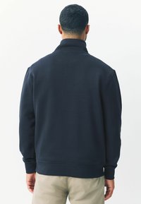 Donkerblauwe pullover sweatshirts met een hoge kraag, geribbelde manchetten en een zachte textuur, met een relaxte pasvorm en minimale details.