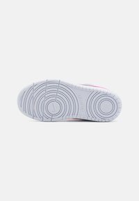 Hvid gummisål til sneakers med et cirkulært mønster, prydet med en let lyserød kant. Tekstureret for godt greb og støtte.