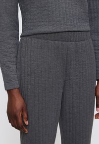 Grau gerippter Zweiteiler mit langärmeliger Bluse und passenden Hosen, aus weichem Stoff mit strukturierter Oberfläche.