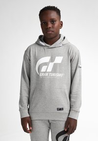 Šedá mikina s velkým bílým logem "Gran Turismo" na hrudi, přední kapsou a šňůrkovou kapucí, doplněná odpovídajícími šedými tepláky.