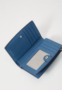 Portafoglio in pelle blu con più scomparti per carte, una tasca trasparente per l'ID e chiusura a scatto. Presenta una texture liscia e dettagli in marrone sui bordi.