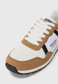 Hvite og brune Jack & Jones sneakers med hvite lisser, sorte detaljer og teksturert såle på hvit bakgrunn.