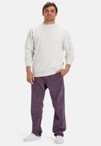 Lys grå hettegenser med rund hals og ribbestrikkede mansjetter, parret med lilla kordfløyelsbukser og hvite sneakers. Minimal merking synlig.