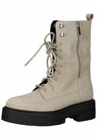 Beige veterschoenen met een chunky zwarte plateauzool, een zijrits en metalen oogjes; gemaakt van glad leer met een gestructureerde afwerking.