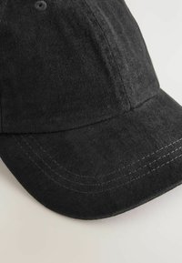 Schwarze Baumwoll-Baseballmütze mit gebogenem Schirm, texturiertem Stoff und kontrastierender Naht entlang der Kanten. Sie verfügt über Belüftungsöffnungen.