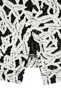 Schwarzer und weißer Stoff mit einem gemusterten Design, das strukturierte, wellenförmige Muster und einen leichten Glanz aufweist. Das Material ist weich mit einer gestrickten Oberfläche.