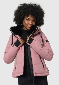 Giubbotto isolato rosa chiaro con cappuccio foderato in pelliccia, tasche con zip e dettagli neri. Presenta un maglione lavorato a maglia con una texture sotto.
