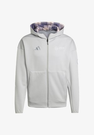 Svijetlosivi dukserica s patentnim zatvaračem i uzorkastim ljubičastim i krem unutarnjim dijelom. Sadrži adidas i Mercedes logotipe na prsima te prednji džep.