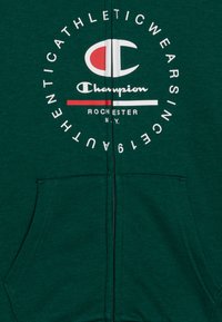 Felpa verde con zip realizzata in tessuto misto cotone, presenta una grande stampa logo bianca con accenti rossi e una tasca frontale.