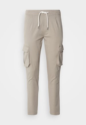 Beige cargo bukser med elastisk talje, snøre lukning, sidelommer og knæpaneler. Har to store sidelommer.