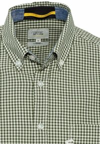 Camisa a cuadros verdes y blancos con cuello abotonado, un bolsillo en el pecho y detalles en tela azul en el interior del cuello. Corte regular.