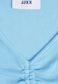 Blaues geripptes Oberteil mit V-Ausschnitt und Raffung in der Mitte, mit einem weißen Etikett, auf dem "JJXX" in navyfarbener Schrift steht.