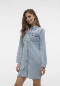 Gaiši zila džinsa krekla kleita ar pogu priekšā, divām krūšu kabatām, garām piedurknēm un brīvu piegriezumu ar taisnu apakšmalu.