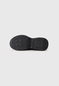 Black rubber shoe sole with patterned tread design, deep grooves for traction, and a round logo embossed in the center.
