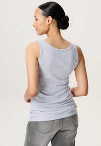 Lichtblauw geribbeld tanktop met een ronde halslijn, een aansluitende pasvorm en een zachte textuur, gecombineerd met grijze jeans. Achteraanzicht met details van het kledingstuk.
