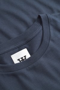 Navy blue cotton t-shirt with a round neck, featuring a smooth texture and a white tag with black lettering at the neckline.
