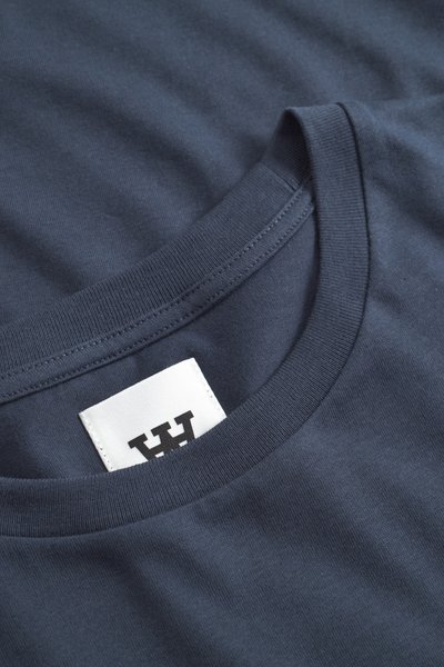 T-shirt en coton bleu marine avec un col rond, doté d'une texture lisse et d'une étiquette blanche avec des lettres noires au niveau du col.