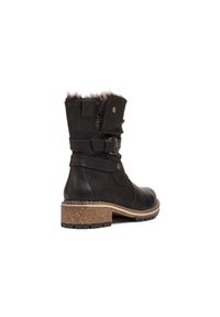 Bottine en cuir noir avec finition en fausse fourrure, sangle ajustable et talon en liège texturé. Dotée d'un bout arrondi et d'une semelle en caoutchouc robuste.