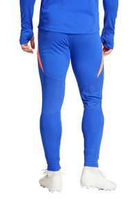 Blauwe sportlegging met een oranje accent, gemaakt van een soepele, rekbare stof met geprofileerde panelen en een aansluitend ontwerp.