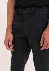 Pantaloni neri in cotone con vestibilità dritta, chiusura con bottoni e tasche laterali. Tessuto liscio, design minimale e aspetto sartoriale.