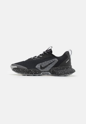 Black athletic shoes with a textured upper, grey accents, and speckled sole; features a prominent Nike logo and gray laces.