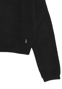 Maglione cropped nero realizzato in morbido tessuto a maglia. Presenta un orlo e polsini a coste, con un piccolo logo argento a forma di "K" sul davanti.