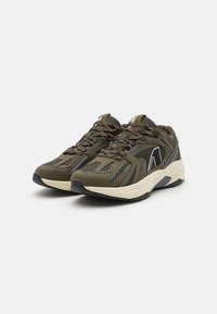 Athletic shoes in olive green with black accents, featuring a textured mesh upper, padded collar, and a cushioned white sole.
