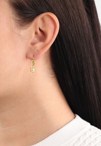 Guldtonade hoopörhängen med en liten rund, texturerad pärla som hänge. Örhängena har en spännsäker stängning för säker användning.