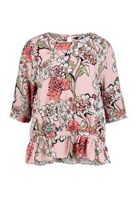Floral peplum top in light pink featuring short sleeves, black outlines, and a mix of red, white, and green floral patterns. Textured fabric.