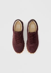 Bordo suede tenisice s teksturiranim finišem, okruglim vrhom, ravnim pertlama i smešnim kožnim akcentom na peti. Gumeni đon s robusnim uzorkom.