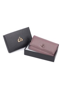 Borsa in pelle di un viola tenue, superficie texturizzata, con un accento a forma di ape sulla parte frontale, presentata in una scatola nera con logo dorato.