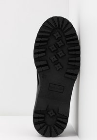 Semelle d'une botte noire avec des crampons profonds et des motifs en forme d'étoile, taille 37, indiquée comme fabriquée en Italie.