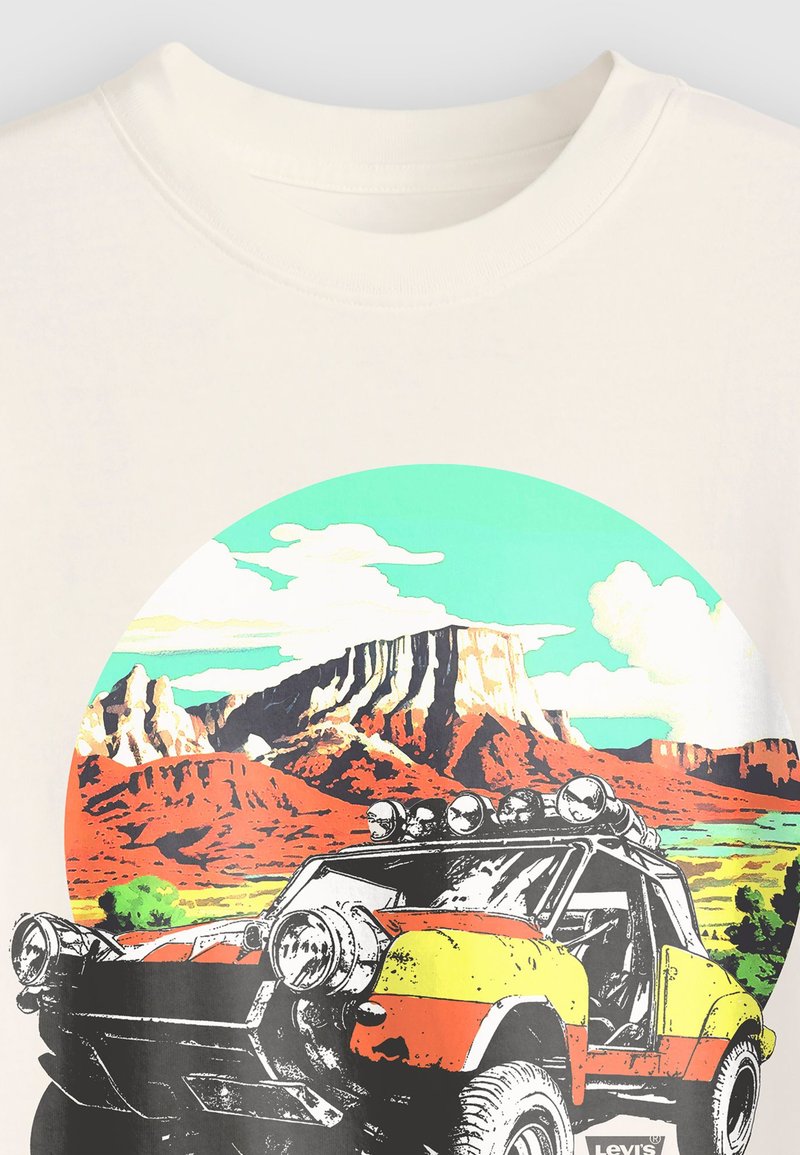 Camiseta blanca con un gráfico colorido de un vehículo todoterreno en estilo cartoon, con montañas y nubes de fondo.